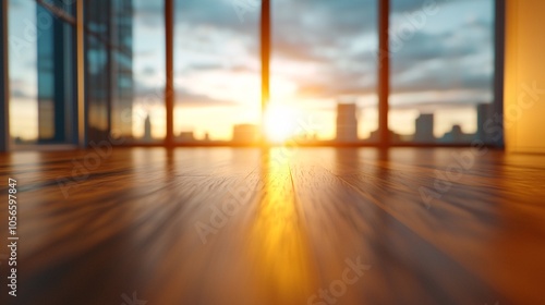 A tranquil sunrise casts a warm glow through large windows, illuminating a wooden floor and showcasing a picturesque city skyline.