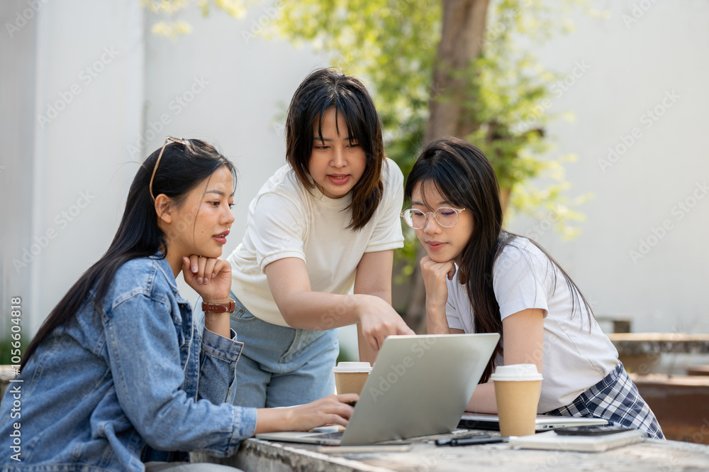 A group of young Asian female college students is focused on discussing a project. A group of young Asian female college students is focused on discussing a project.