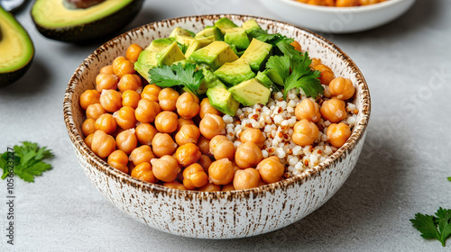 Delicious grain bowl featuring chickpeas, quinoa, avocado, and fresh herbs on a light background.