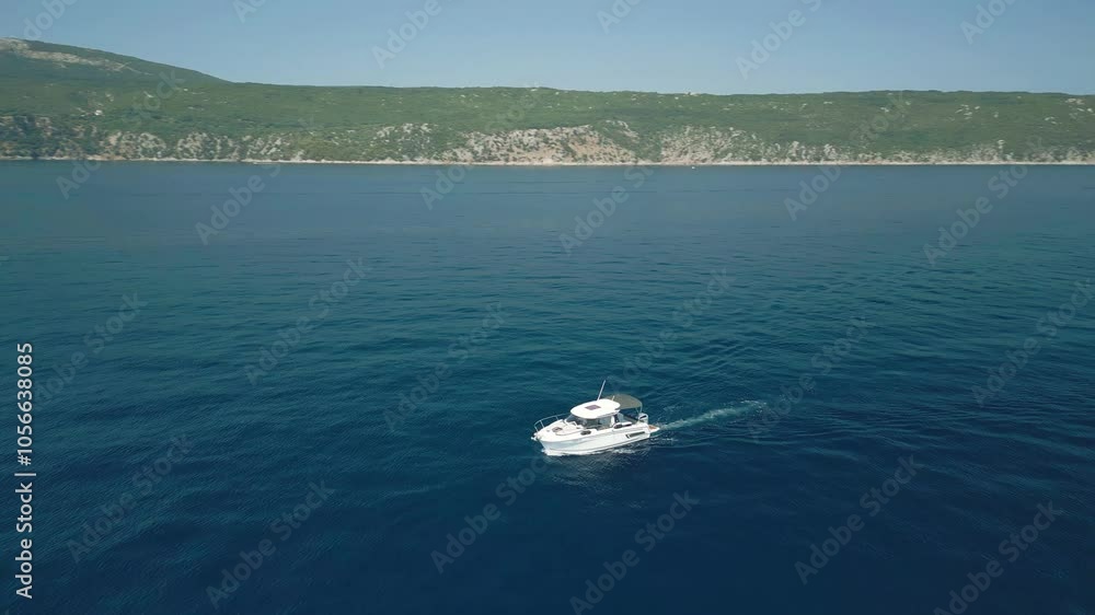 A boat cruises through the calm blue sea with green hills in the background A boat cruises through the calm blue sea with green hills in the background
