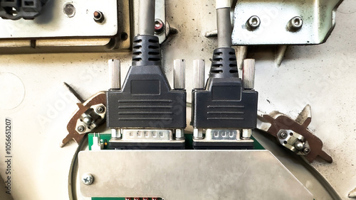 A close-up of two connected serial port cables on an industrial device, showcasing connectors and technical wiring.

 photo