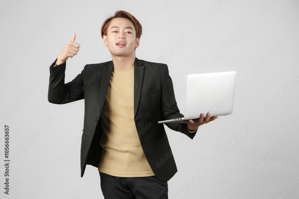 portrait of asian businessman holding laptop computer wearing suit giving thumb up gesture on isolated background portrait of asian businessman holding laptop computer wearing suit giving thumb up gesture on isolated background