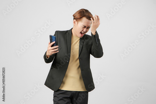 portrait of angry mad asian businessman wearing holding mobile on isolated background photo