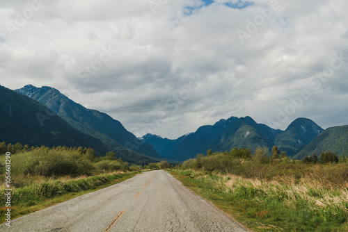 Scenic rural road with mountain silhouette against cloudy sky