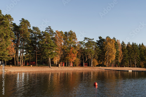 Sandy lakeside with trees against blue sky at sunset photo