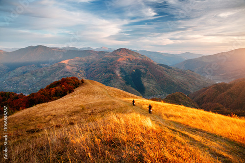 Two motorcyclists ride down a mountainside in the evening sun. Carpathian mountains, Ukraine.