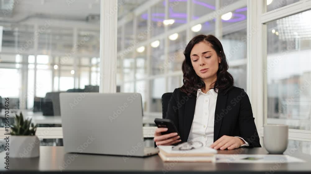 Stressed businesswoman in a suit holds credit card and uses phone, makes online payment, has problem with transaction. Office worker has financial problems or difficulty paying bills. Stressed businesswoman in a suit holds credit card and uses phone, makes online payment, has problem with transaction. Office worker has financial problems or difficulty paying bills.