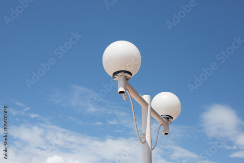 Two white street lights are hanging from a metal pole photo