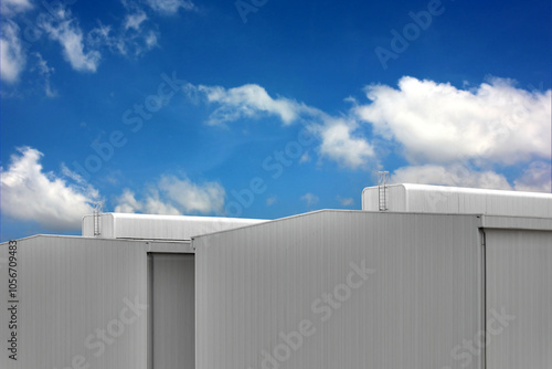 corrugated metal wall with ventilation dome of factory warehouse building on blue sky white cloud. corrugated seamless pattern abstract background photo