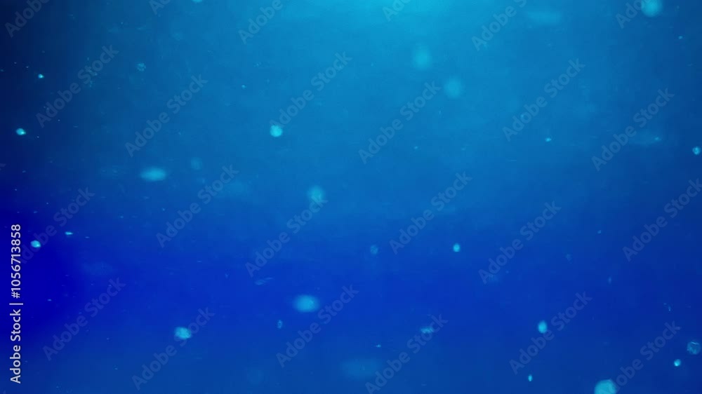 Small abstract particles flowing in liquid against blue background. Slow motion. Small abstract particles flowing in liquid against blue background. Slow motion.