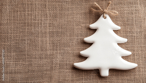 White ceramic Christmas tree ornament on textured fabric background