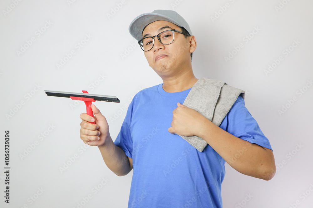 A young Asian man wearing cleaning work clothes cleaning windows and looking at the camera A young Asian man wearing cleaning work clothes cleaning windows and looking at the camera