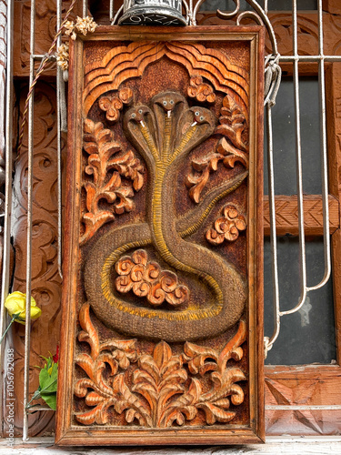 A wooden snake carving with three heads and a flower in the foreground