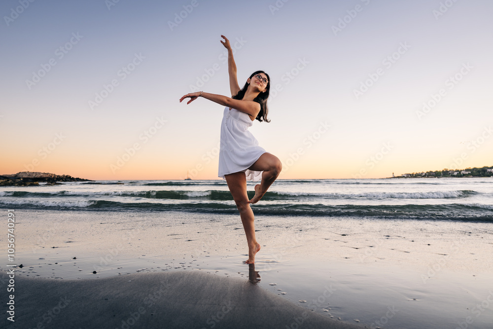 Woman dancing barefoot on the beach at sunset in white dress Woman dancing barefoot on the beach at sunset in white dress