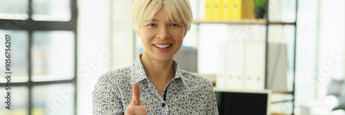 Smiling employee showing approval sign standing in office