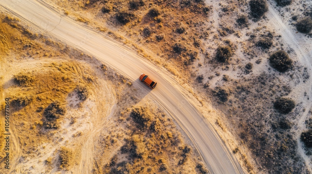 Fototapeta premium Aerial perspective of a vehicle on a winding road through a desert landscape