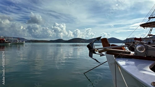 Static view of the Marina Elouda in Greece, part of a boat with an anchor on the right and mountains in the background, copy space photo