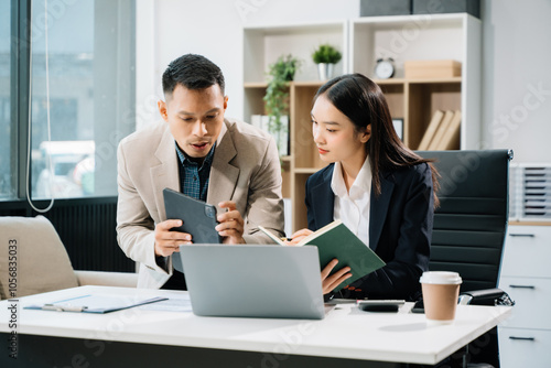Two business workers talking on the smartphone and using laptop at the office..