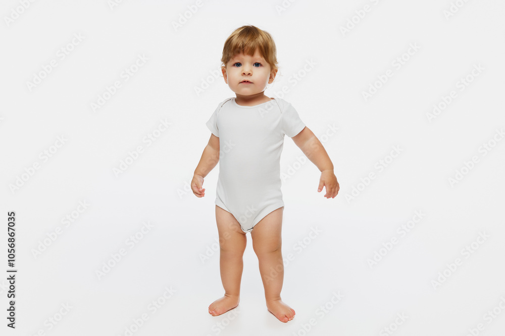 Curious baby standing with arms slightly raised, against white studio background, capturing innocence and wonder of early childhood. Concept of parenthood, natural beauty, love and care. Ad. Curious baby standing with arms slightly raised, against white studio background, capturing innocence and wonder of early childhood. Concept of parenthood, natural beauty, love and care. Ad.