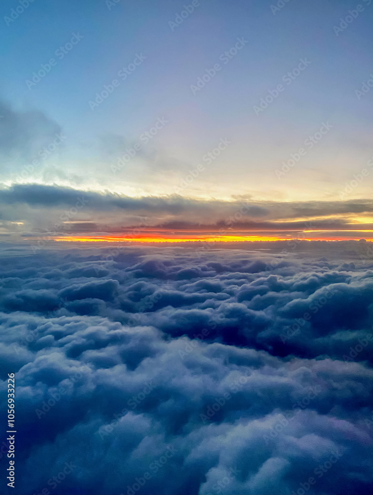 Sunset above the clouds, view from the window of an airplane