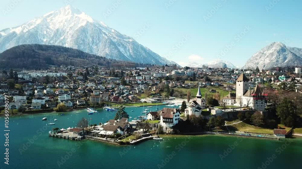 Stunning drone view of Spiez, by the Lake Thun, Switzerland with snowy mountains on the horizon.