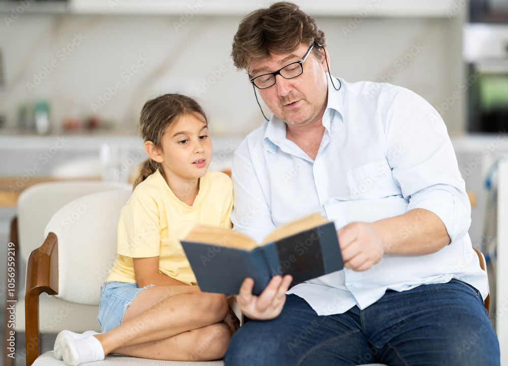 Father reads book to little cute daughter, spend leisure enjoy good life hobby and pastime at home. Fatherhood, upbringing, children development Father reads book to little cute daughter, spend leisure enjoy good life hobby and pastime at home. Fatherhood, upbringing, children development