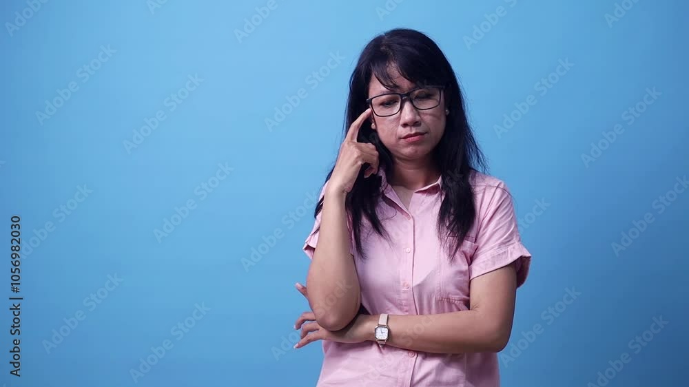 Happy excited surprised young Asian woman find something on aside. Isolated on blue background in studio. Happy excited surprised young Asian woman find something on aside. Isolated on blue background in studio.