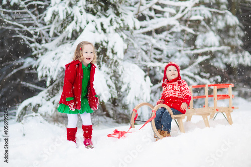 Kids in Christmas clothes in winter forest.