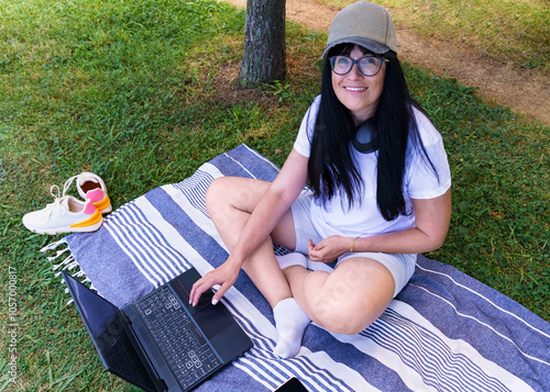 Beautiful woman smiling distractedly at her laptop in the fresh air photo