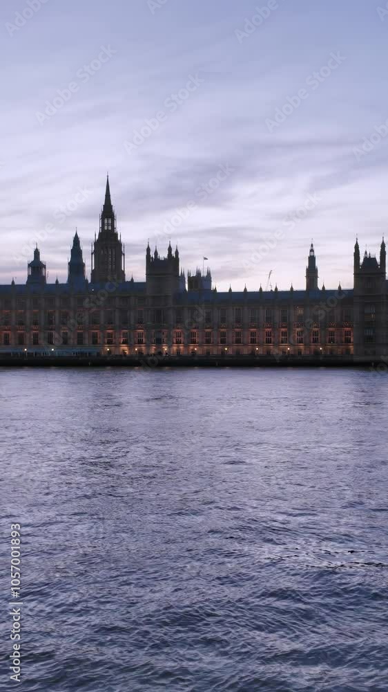 Evening view of the Houses of Parliament in London, with Big Ben illuminated at blue hour, reflecting on the Thames River. Panning left to right. Vertical video Evening view of the Houses of Parliament in London, with Big Ben illuminated at blue hour, reflecting on the Thames River. Panning left to right. Vertical video