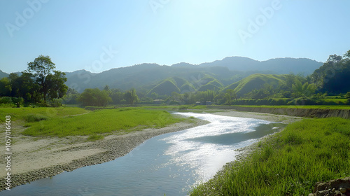 A serene river winding through a lush green valley with rolling hills in the background.