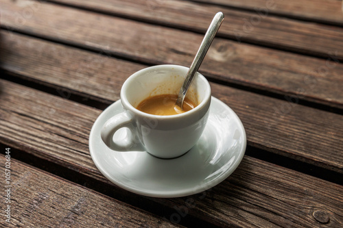 tazzina piena di caffè espresso, di giorno, dopo pranzo, su un tavolo di legno, all'aperto photo