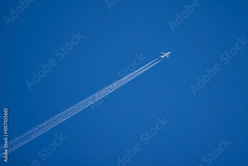 a white plane that leaves traces in the blue sky