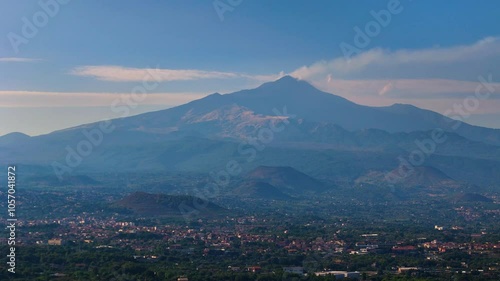 Aerial pull-back view of Mount Etna in Sicily with smoke from the crater and small villages in the foothills photo