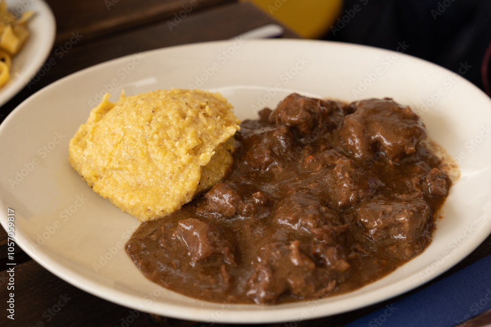 piatto con pezzetti di carne di manzo, cotta, con sugo e polenta piatto con pezzetti di carne di manzo, cotta, con sugo e polenta