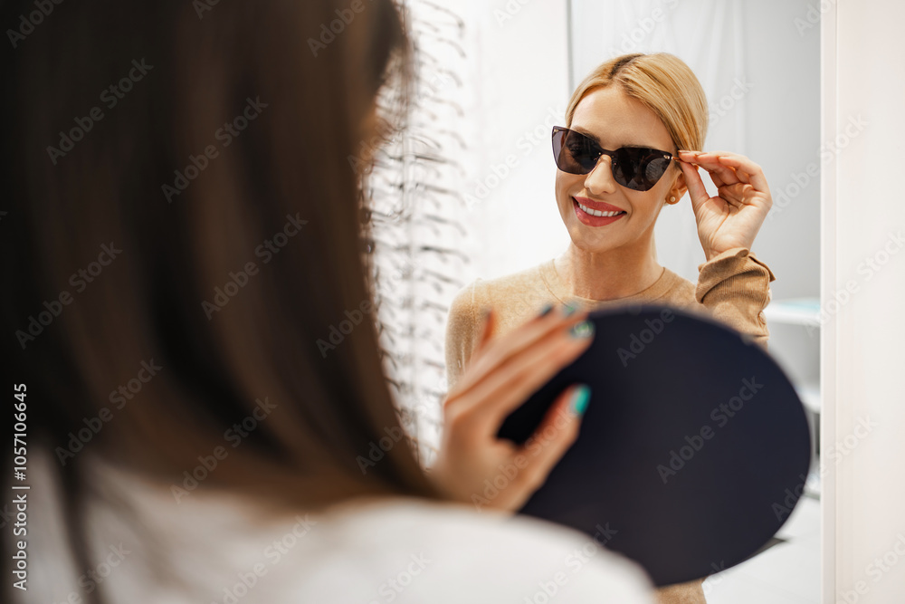 Εκτύπωση καμβά Beautiful and fashionable woman choosing eyeglasses frame in modern optical store