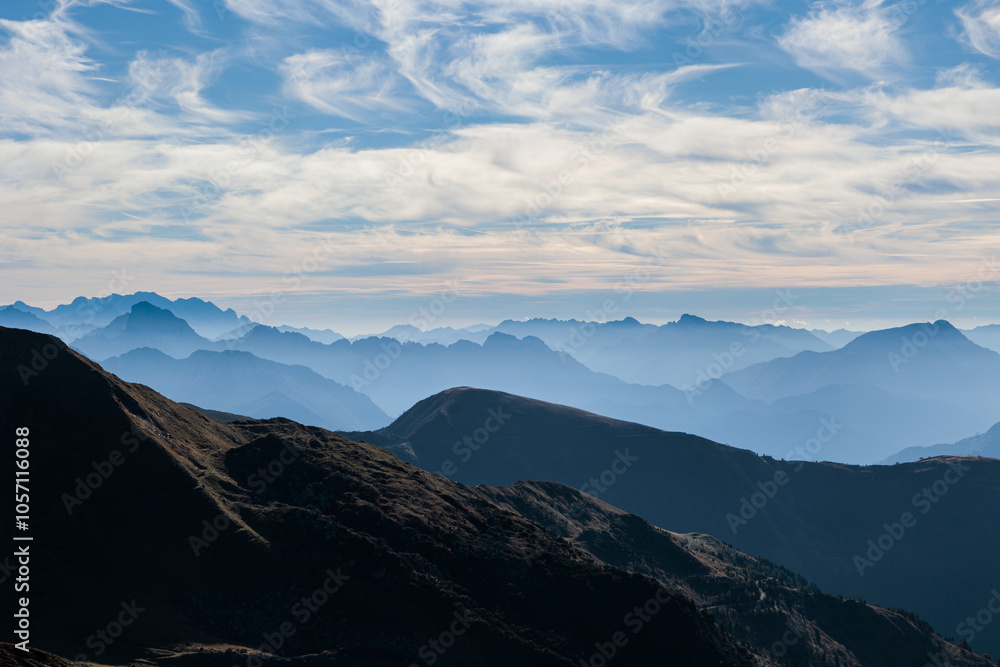 Obraz premium catene montuose nel nord Italia che si estendono verso l'orizzonte, avvolte da nuvole basse e da una leggera foschia, sotto un cielo leggermente nuvoloso, di mattina, in autunno