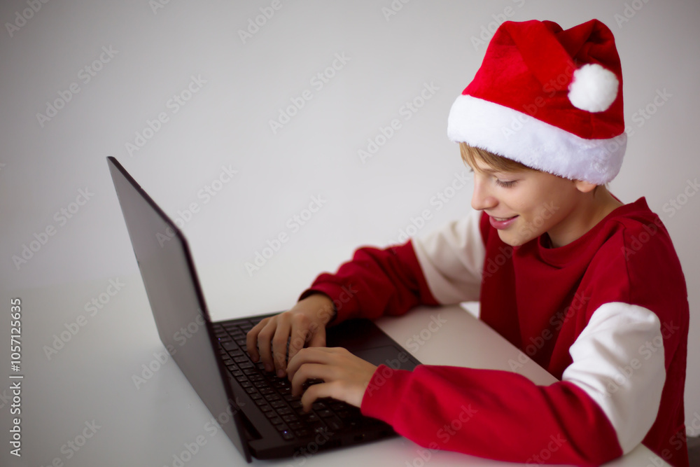 Happy Boy in Santa Hat Typing on Laptop Happy Boy in Santa Hat Typing on Laptop