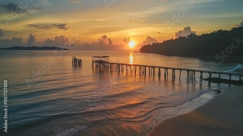 A view of a fiery sunrise over an old jetty at Tanjung Langsat beach in Johor. This image may feature noise and blurry clouds from long exposure, along with soft focus and low lighting. photo