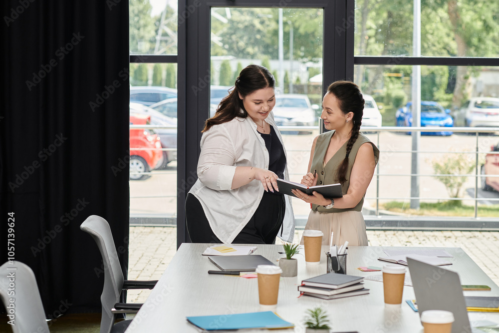 Two professional women discuss ideas while reviewing documents in a bright office space. Two professional women discuss ideas while reviewing documents in a bright office space.