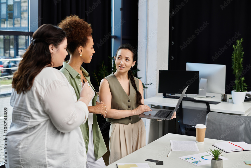 Three stylish professionals engage in a discussion while working on a laptop in the office. Three stylish professionals engage in a discussion while working on a laptop in the office.