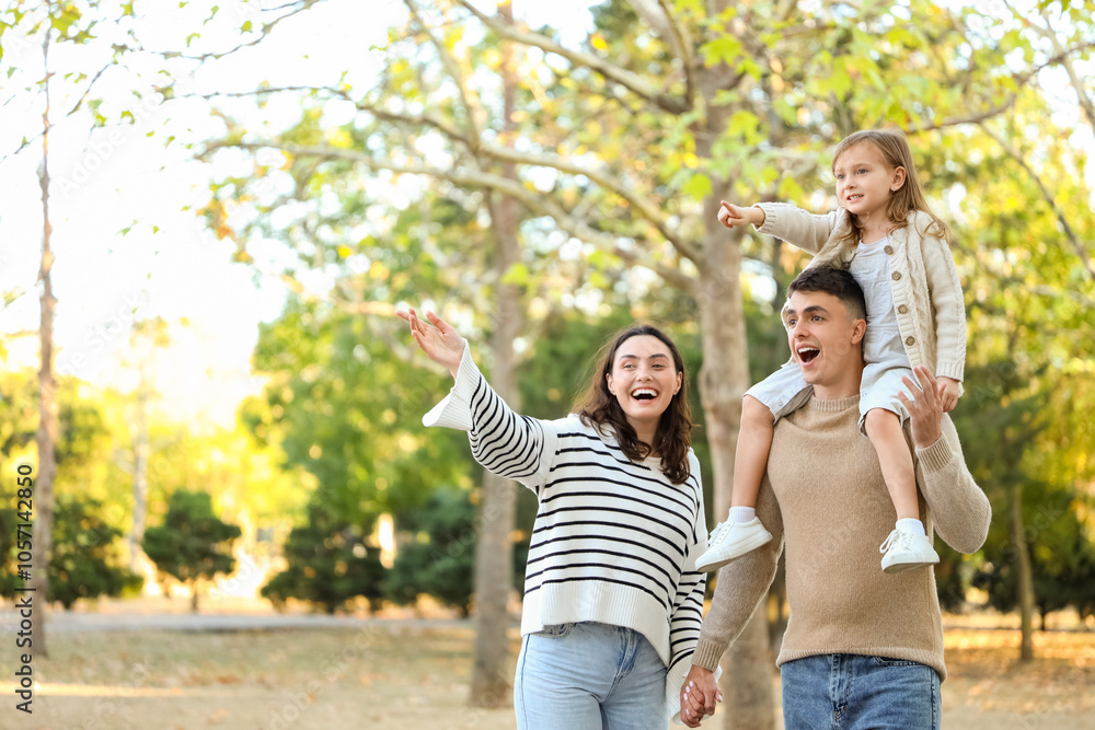 Fototapeta premium Happy family pointing at something while walking in beautiful autumn park
