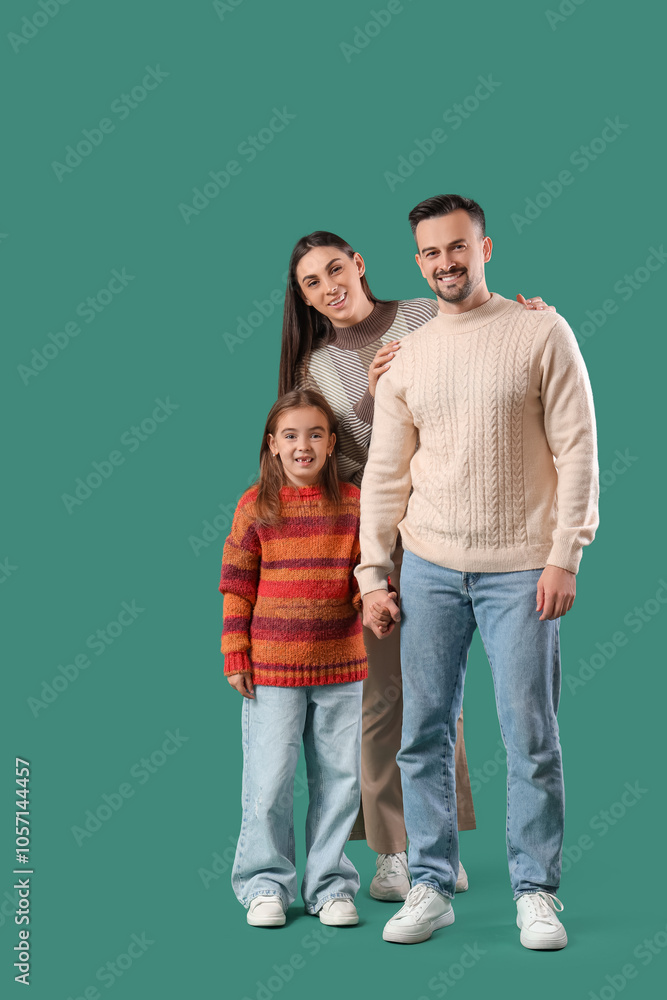 Happy family with their daughter in sweaters on green background Happy family with their daughter in sweaters on green background