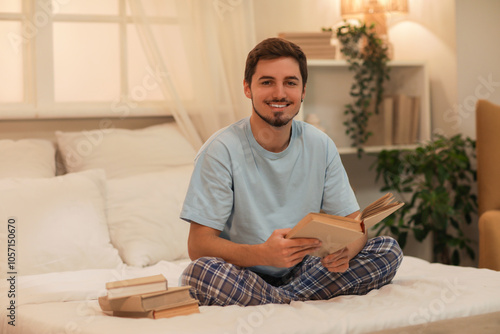 Young man reading book in bedroom at night