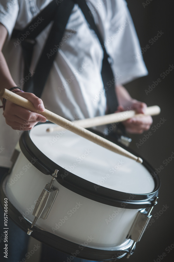 Obraz premium A person is playing a drum with a wooden stick