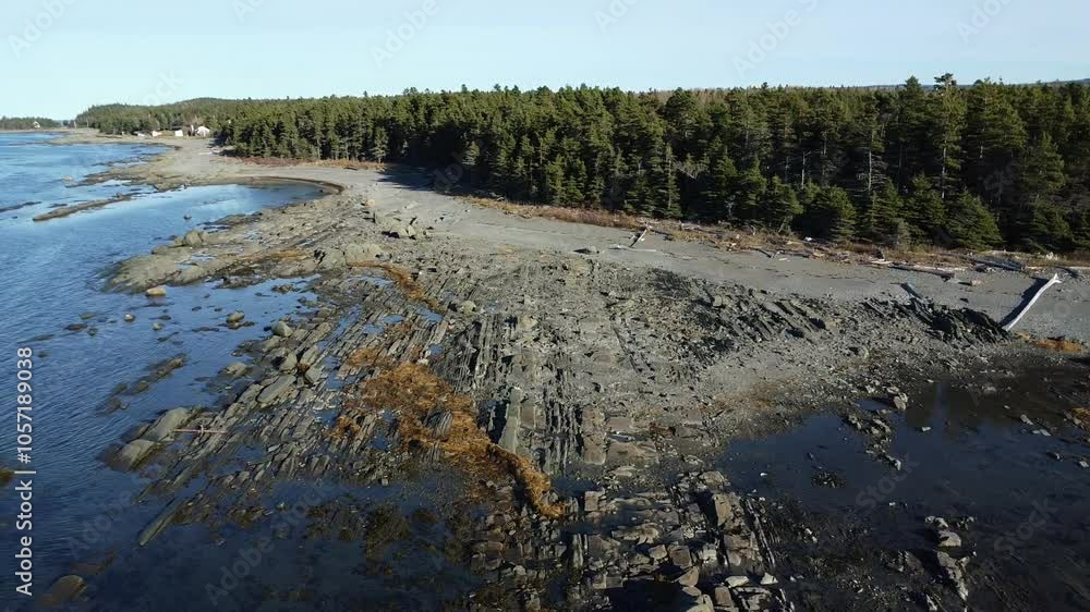 Quick flight along a rocky and sandy beach of the majestic Saint-Laurent River, bordered by the forest. Pointe-Leggatt. Metis-sur-Mer.