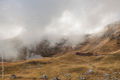 vista panoramica su un ambiente di alta quota, in montagna, tra le cime erbose lungo le catene montuose nelle Alpi Italiane, coperte dalle nuvole basse, di giorno, in autunno  photo