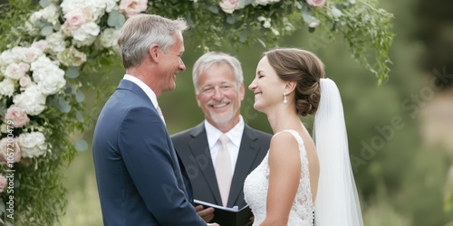 A joyful wedding ceremony featuring a couple exchanging vows with a smiling officiant and floral decoration.
