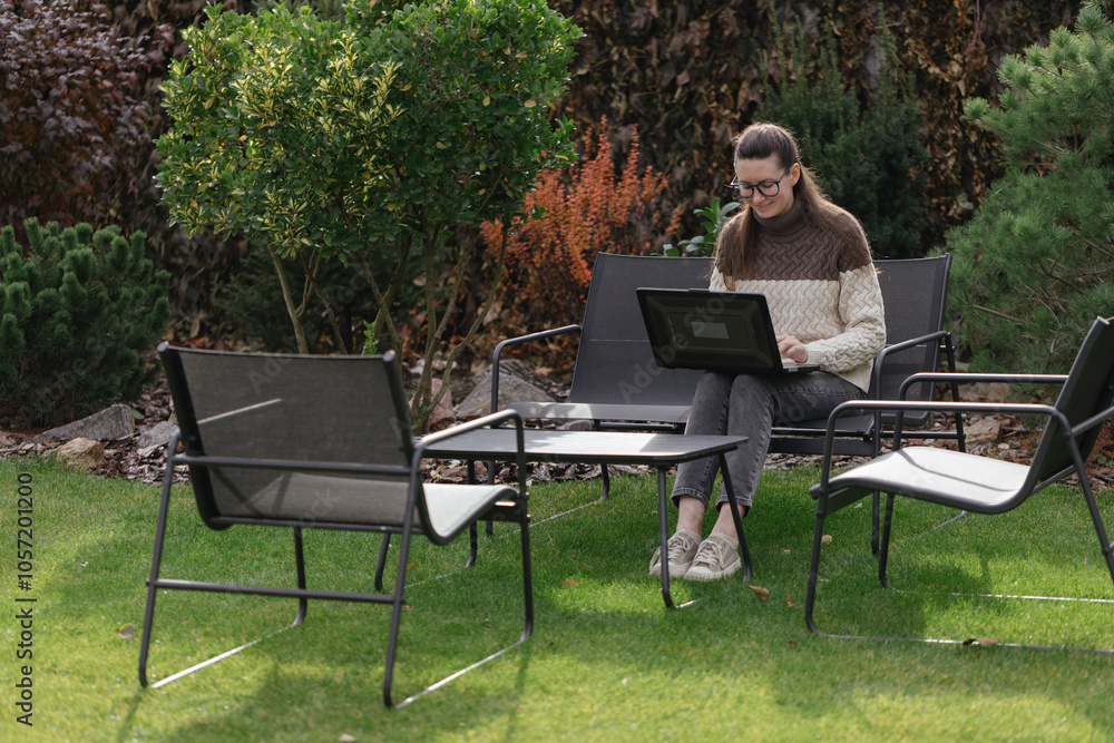 Woman working with a laptop in the backyard Woman working with a laptop in the backyard