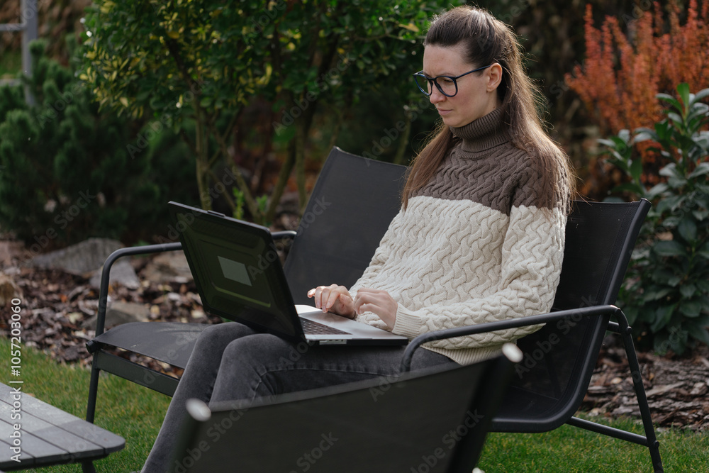 Woman working with a laptop in the backyard Woman working with a laptop in the backyard